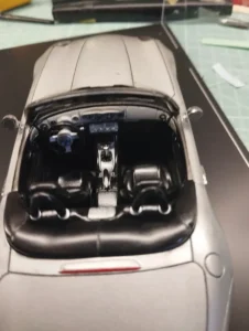 Vue de l'intérieur d'une maquette de BMW Z8 posée sur un bureau encombré.